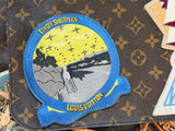 A Louis Vuitton monogram canvas pouch or bag featuring a circular embroidered patch with a blue border, yellow and gray design, and text reading 'CNDY EVERGHAN' and 'NILLIAD VICTOR'.