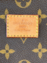 Close-up of a Louis Vuitton monogram canvas surface with a stitched leather brand patch reading 'LOUIS VUITTON PARIS made in France'.