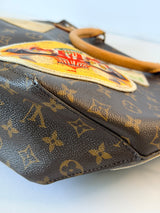 Close-up of a Louis Vuitton monogram canvas handbag with a colorful embroidered patch and a tan leather handle on a light background.