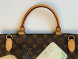 Close-up of a Louis Vuitton monogram handbag in brown coated canvas with tan leather handles and silver-tone hardware, shown against a plain white background.