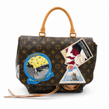 A Louis Vuitton monogram canvas handbag with tan leather top handles and multiple colorful embroidered patches on the front, photographed on a clean white background.